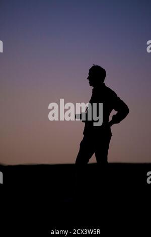 Figure solitaire avec la caméra silhouettée contre le ciel de la région de Kaluts du désert LUT. L'endroit le plus chaud sur terre. Iran. Modèle validé Banque D'Images