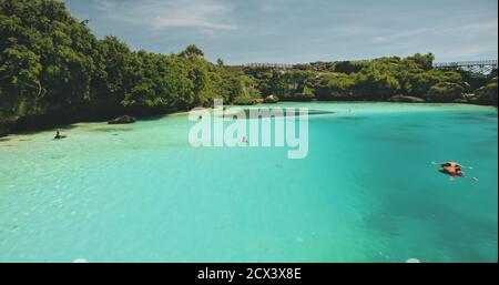 Vue aérienne en gros plan sur le lac limpid sur la falaise verte de la rive de l'océan. Paysage indonésien pittoresque de la lagune de Weekuri, île de Sumba avec végétation tropicale et arbres. Prise de vue en lumière douce de qualité cinématographique Banque D'Images