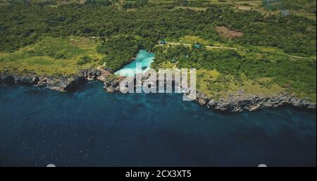 Lac d'azur sur la côte rocheuse verte à la baie de la mer en vue aérienne. Paysage tropical de l'île de Sumba, Indonésie. Magnifique lagon d'eau salée dans la verdure des arbres et des plantes sur la rive de la mer Banque D'Images