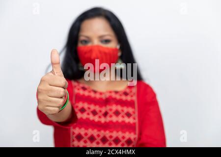 Portrait d'une femme indienne montrant son pouce comme signe de succès et d'approbation, femme debout contre le mur blanc, femme portant la protection Covid 19. Banque D'Images