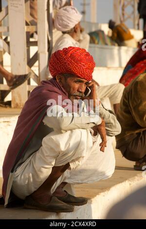 Rajasthani homme sur le téléphone portable distinct de style local robe. Pushkar, Rajasthan, Inde Banque D'Images