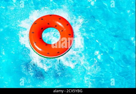 Melon d'eau gonflable rouge avec des graines bouée splash tombent dans le vue sur la piscine depuis le dessus Banque D'Images