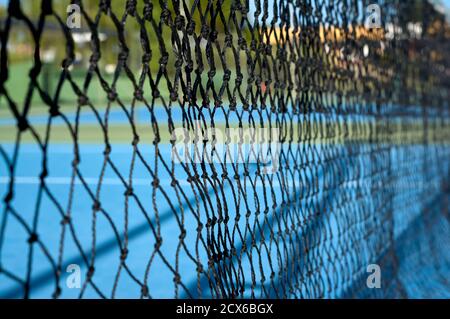 détail d'une vue sur un court de tennis synthétique bleu via le réseau central Banque D'Images