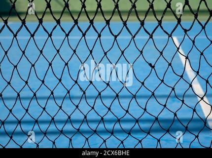 détail d'une vue sur un court de tennis synthétique bleu via le réseau central Banque D'Images