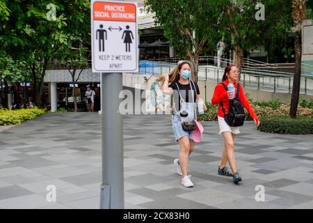 Taguig, région de la capitale nationale, Philippines. 30 septembre 2020. Un panneau au trottoir rappelle aux gens d'observer la distance de 2 mètres comme protocole de santé. Cependant, les deux dames marchent côte à côte à moins d'un mètre de distance dans la ville de Taguig le 30 septembre 2020. Crédit : George BUID/ZUMA Wire/Alay Live News Banque D'Images