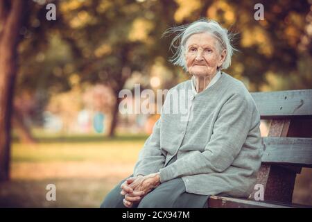 Portrait d'une femme âgée dans un parc d'automne regardant l'appareil photo Banque D'Images