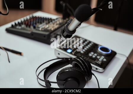 Lieu de travail de l'hôte radio. Gros plan des écouteurs, du microphone et du bureau de mixage du son sur la table dans un studio d'enregistrement ou une salle de diffusion Banque D'Images