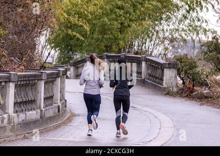 Deux jeunes femmes qui font du jogging lors d'une journée pluvieuse dans le parc Stanley, Vancouver, C.-B., Canada Banque D'Images