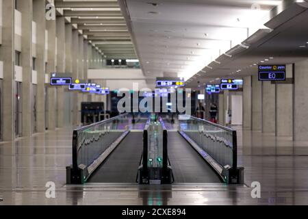 Vue sur une paire de passerelles mobiles vides en long hall d'un aéroport en fin de soirée Banque D'Images