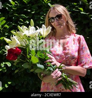 Portrait d'une femme mûre dans un parc avec bouquet de fleurs colorées Banque D'Images