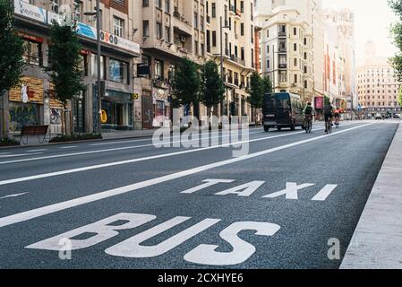 Madrid, Espagne - 23 mai 2020 : cyclistes qui se trouvent au milieu des bâtiments de l'avenue Gran via pendant le confinement pandémique de Covid-19. Lumière du soleil sur l'arrière-plan Banque D'Images