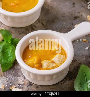 Trois petits bols en céramique de soupe de carottes, servis avec du basilic frais et des croûtons sur fond de fer rouillé. Style rustique sombre. Image carrée Banque D'Images