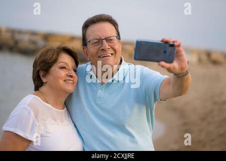 bonne femme retraité et son mari prenant la marche romantique de prendre selfie - heureux retraité couple mûr marchant sur la plage pendant les vacances prenant sel Banque D'Images