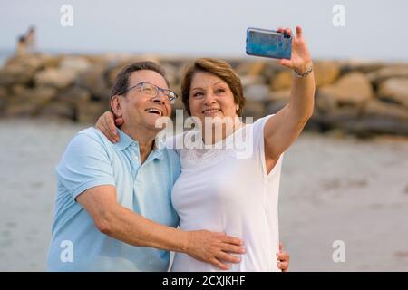 bonne femme retraité et son mari prenant la marche romantique de prendre selfie - heureux retraité couple mûr marchant sur la plage pendant les vacances prenant sel Banque D'Images