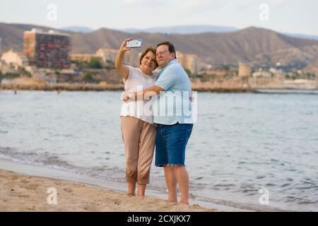 bonne femme retraité et son mari prenant la marche romantique de prendre selfie - heureux retraité couple mûr marchant sur la plage pendant les vacances prenant sel Banque D'Images