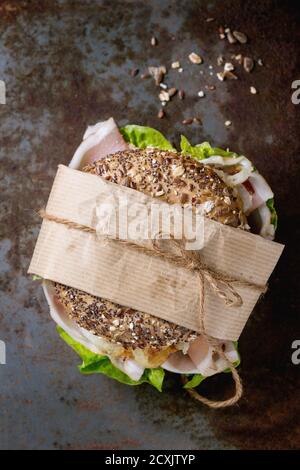 Bagel de grains entiers tapissés avec oignon frit, salade verte et jambon prosciutto de vieux fer rouillé background. Vue d'en haut Banque D'Images