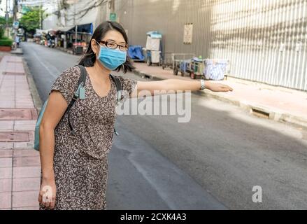 Une touriste asiatique salue un taxi dans la ville de Bangkok en Thaïlande, une femme portant un masque médical dans la rue le matin. Banque D'Images