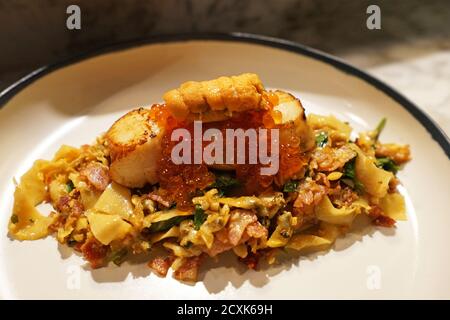 Gros plan sur les pâtes Surf et Turf garnies d'œufs de saumon, de bacon, d'Uni (oursin de mer) et de pétoncles poêlés Banque D'Images