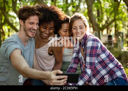 De jeunes amis heureux emportant un selfie sur un smartphone en plein air Banque D'Images