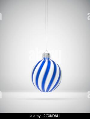 Boule de Noël à rayures torsadées blanches et bleu roi suspendue. Arrière-plan ombré blanc. Décoration de Noël, concept d'atmosphère festive. Banque D'Images