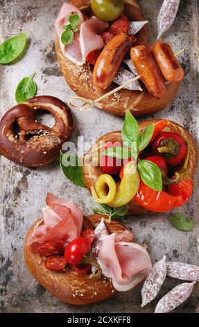 Variété de collations de viande, saucisses frites wienerwurst, jambon, piments marinés servis dans les Bretzels salés avec le basilic plus vieux métal arrière-plan. Banque D'Images