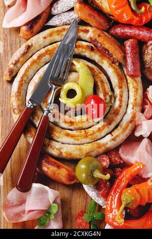 Variété d'en-cas de viande saucisses frites, wienenerwurst, jambon, piments marinés servis dans des bretzels salés avec des couverts sur la planche à découper en bois au-dessus de da Banque D'Images