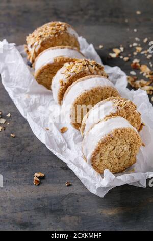 Ensemble de sandwiches faits maison à la crème glacée dans des biscuits d'avoine avec chapelure de sucre d'amande sur papier de cuisson sur fond de texture métallique sombre. Gros plan Banque D'Images