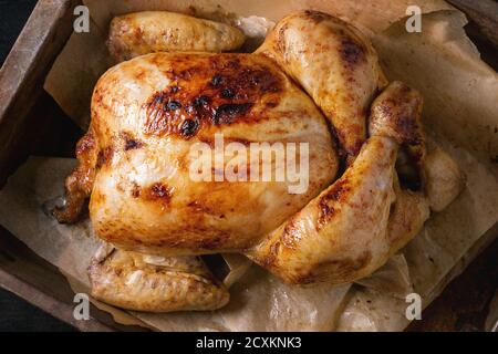 Tout cuit grillé poulet biologique sur support papier dans le vieux four noir sur fond de bois brûlé. Vue de dessus, Close up Banque D'Images