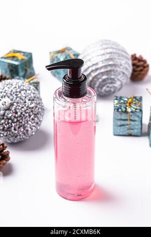 Gel rose pour le maquillage pour le visage savon liquide propre dans un flacon distributeur en plastique près des décorations et jouets du nouvel an de Noël Banque D'Images