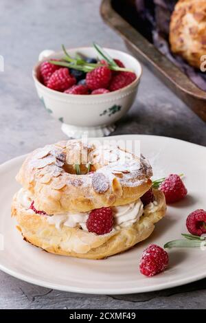 Remplir et vider des pâte à choux gâteau Paris Brest avec des framboises, l'amande, le sucre en poudre, le romarin sur la plaque et four avec des baies plus gra Banque D'Images