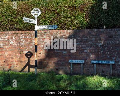 Ancienne circonscription de l'Ouest du Yorkshire cocarde signpost avec le nom du village Et la grille de référence par un mur de briques dans Whixley près Knaresborough North Yorkshire Engla Banque D'Images