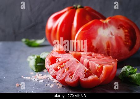 Ensemble et les tranches de tomates Coeur de boeuf bio. Émincé de Tomates avec basilic et sel rose sur gris bleu metal texture background. Close up avec l'espace Banque D'Images