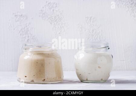 Levain de seigle et de blé dans des pots en verre pour cuire du pain maison sur fond de béton gris. Banque D'Images