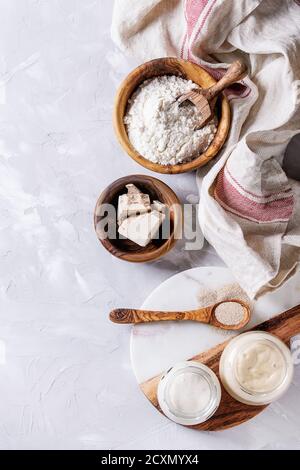 Levain de seigle et de blé en pots de verre, levure fraîche et instantanée, bol en bois d'olive de farine pour cuire du pain maison. Avec cuillère, table de service, cuisine Banque D'Images