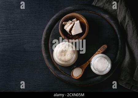 Levain de seigle et de blé en pots de verre, levure fraîche et instantanée pour cuire du pain maison. Avec cuillère, plateau de service, textile sur bois noir brûlé Banque D'Images