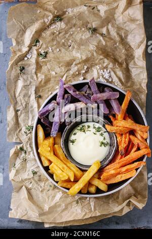 Variété de pommes de terre traditionnelles frites de pommes de terre, carotte pourpre, servi avec sauce au fromage blanc, le sel, le thym dans un bol sur papier cuisson bac en métal gris Banque D'Images