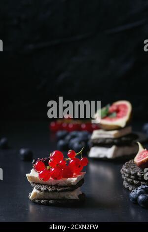 Les craquelins avec du charbon noir camembert fromage brie et petits fruits, bleuets dewberry, de groseille rouge et les tranches de figues, servi sur plateau vintage sur dark meta Banque D'Images