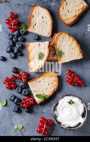 Variété d'ingrédients pour la préparation de sandwichs dessert avec du pain grillé, des baies et du fromage à la crème. Cassis, bleuets sur fond gris en métal Banque D'Images