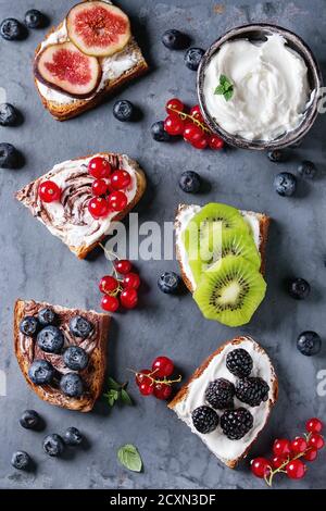 Variété de sandwichs dessert aux fruits rouges et crème de fromage et tourbillon de chocolat. De groseille rouge, de bleuets, de tranches de kiwi, figs sur métal gris backgroun Banque D'Images