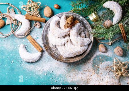 Biscuits aux noix de Noël faits maison croissant de sucre en poudre dans la décoration de vacances et sapin sur la surface de texture en bois turquoise avec espace de copie. Haut Banque D'Images