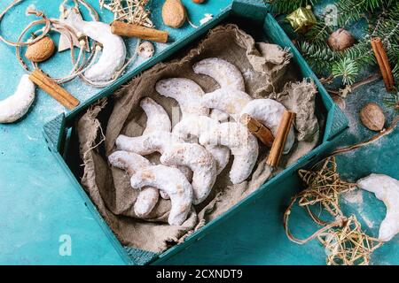 Biscuits maison aux noix de Noël croissant avec sucre en poudre en bois chausson avec décoration d'étoile de vacances et sapin sur turquoise surface de texture du bois Banque D'Images