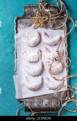 Biscuits maison aux noix de Noël croissant avec sucre en poudre sur vintage plateau en métal comme sapin avec étoile de décoration de vacances et enfilez la guirlande sur le gazon Banque D'Images