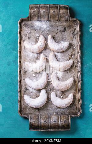 Biscuits maison aux noix de Noël croissant de sucre en poudre sur plateau métallique vintage comme sapin sur fond turquoise à texture boisée avec espace de copie. Banque D'Images
