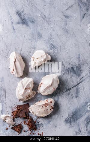 Pâtisserie dessert français maison meringue au chocolat servi avec du chocolat noir et de la poudre de cacao sur fond de texture de béton gris. Haut Banque D'Images