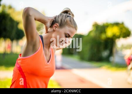 La jeune femme fait de l'exercice en plein air. Elle étire son corps et s'échauffe pour le jogging. Banque D'Images