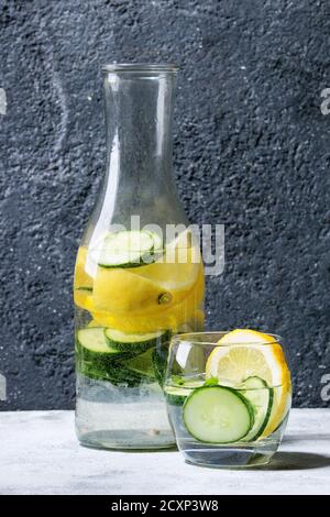 Agrumes concombre sassy sassi eau pour le détox dans une bouteille en verre sur fond de texture grise. Alimentation propre, concept de mode de vie sain, lumière du soleil Banque D'Images