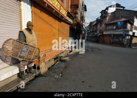 An Indian policeman keeps guard in front of the closed shops during a curfew in Srinagar February 12, 2013. India hanged Mohammad Afzal Guru, a Kashmiri man, on Saturday for an attack on the country's parliament in 2001, sparking clashes in Kashmir between protesters and police. Security forces had imposed a curfew in parts of Kashmir and ordered people off the streets. REUTERS/Danish Ismail (INDIAN-ADMINISTERED KASHMIR - Tags: POLITICS)