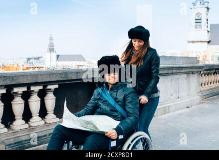 image vraiment émouvante avec mise au point sur une femme qui pousse un fauteuil roulant extérieur avec un ami handicapé Banque D'Images