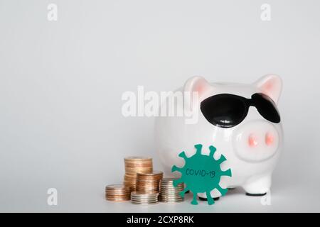 risque d'économies financières dues à un virus pandémique. banque de porc dans un masque sur fond blanc. pièces Banque D'Images