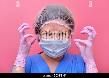 Une femme médecin dans un uniforme bleu est en colère, concept. Portrait d'une infirmière sur fond rose, gros plan. Restez à la maison. Banque D'Images